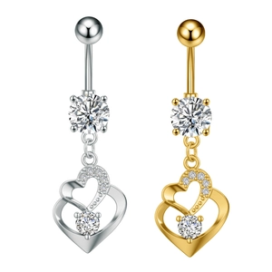 Detalle de piercings de ombligo en plata y oro con colgantes de corazón y circonitas
