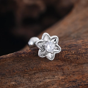 Macro view of silver flower cartilage stud with cubic zirconia and matte petals