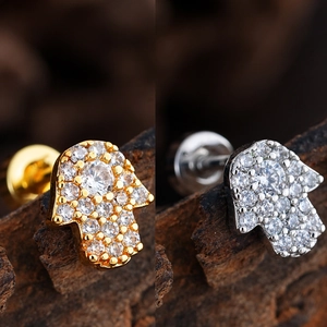 Detalle macro de pendientes Hamsa con acabados en oro y plata y circonitas en micro-pavé