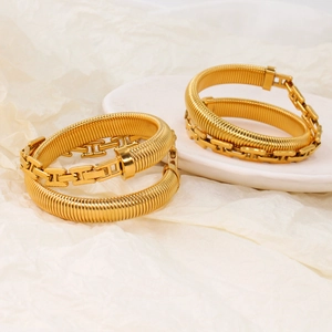 Close-up of gold-plated titanium stretch bracelets with H-shaped link and snake chain detail