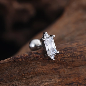 Macro detail of stainless steel tragus stud with rectangular zircon on aged wood