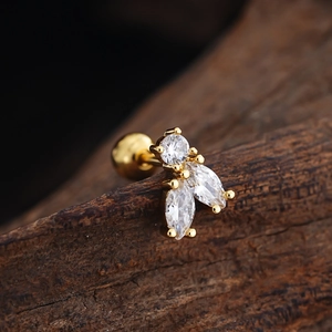 Macro view of gold zircon stud earring with round and marquise stones on wood