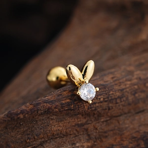 Detailed macro view of a golden rabbit ear stud with a sparkling round zircon and ball back