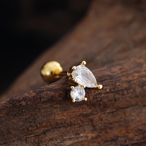 Macro view of gold stud earring with teardrop zircon on a natural wood surface