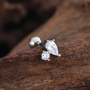 Macro shot of silver stud earring with pear and round cubic zirconia on wood background