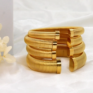 Ensemble de quatre bracelets joncs en acier plaqué or 18 carats sur tissu en soie blanche