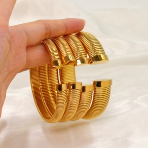 Détail macro de bracelets spirales Tubogas dorés sur un fond en satin blanc plissé
