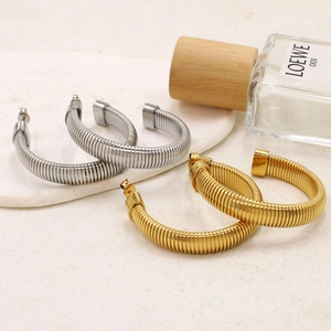 Chic gold and silver spiral spring hoop earrings set on an elegant cream tray