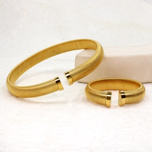 Detail of golden C-shaped open bangles with spring-like textured coiled wire design