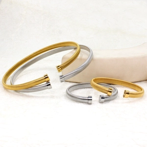Detail of four spiral spring open bangles in gold and silver finish on display stand