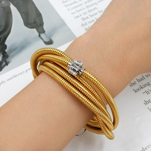 Close-up of gold layered spiral bracelet featuring inlaid rectangular cubic zirconia stones