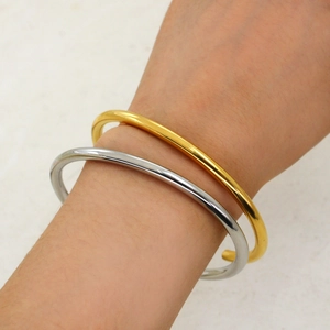 Detail of stacked minimalist gold and silver open bangles with high-polished finish