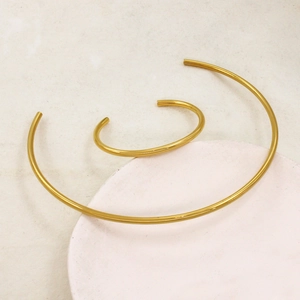 Detail of 18K gold plated minimalist collar necklace and open cuff bracelet jewelry set
