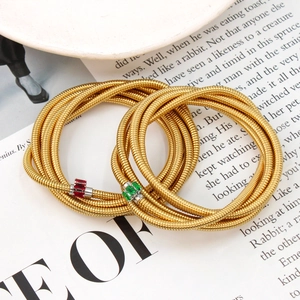 Macro detail of multi-layer gold snake chain bracelet with red and green zircon stones