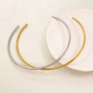 Minimalist C-shape choker set in gold and silver polished stainless steel on a stone tray