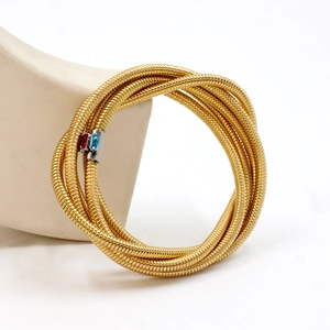 Detail of 18K gold multilayer wrap bracelet with red and blue zircon gemstones