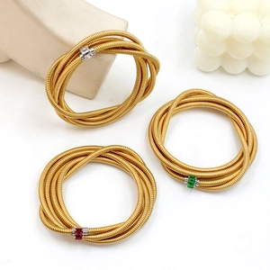 Detail of layered gold snake chain bracelets with colorful zircon stone insets