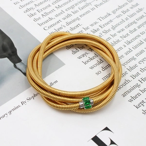 Detail view of multi-layer gold snake chain bracelet with green zircon embellishment