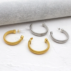 Détail de grandes boucles d'oreilles créoles C avec texture spirale en or et argent
