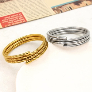 Detail view of gold and silver spring coil bracelets on a stone tray with vintage paper