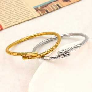 Detail of gold and silver snake bone spring bangles with metallic texture on stone platform