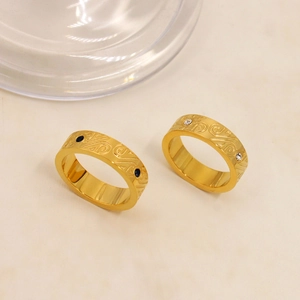 Dettaglio di anelli in acciaio al titanio oro 18K con rilievo curvo e zirconi incastonati