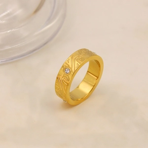 Dettaglio anello in titanio oro 18K con motivi a spirale incisi e zircone incastonato