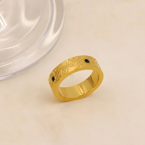 Dettaglio anello placcato oro 18K con motivi a volute e gemme verdi incastonate