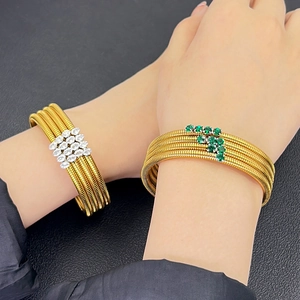 Detail of multi-layer golden spiral bracelets with sparkling white and green zircon stones