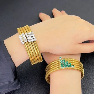 Detailed close-up of multilayered gold tubogas bracelets with white and green zircon stones
