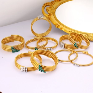 Layered gold spiral bracelet with green and white zircon stones on vintage mirror
