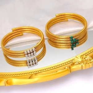 Detail of multi-layer spiral gold bangles with zircon and green gemstones on tray