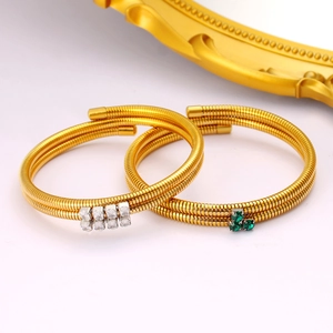 Detail of gold-plated tubogas wrap bracelets featuring zircon and green gemstone accents