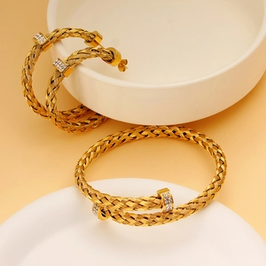 Nahaufnahme eines goldenen geflochtenen Schmucksets mit Zirkonia auf Keramikschalen