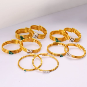 Detailed close-up of 18K gold plated multi-layer spiral bracelets with emerald and zircon