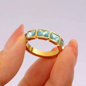 Squisito anello in zircone dorato con cinque cristalli blu rettangolari sulla mano