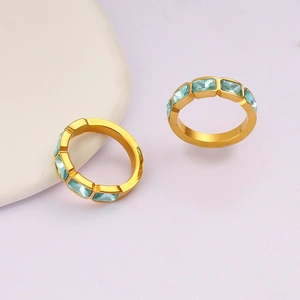 Dettaglio di due anelli placcati in oro con pietre di zircone rettangolari blu