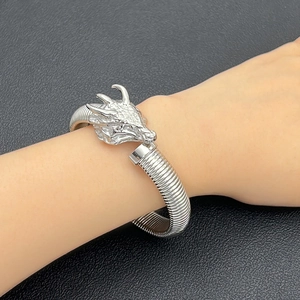 Primer plano detallado de una pulsera de cabeza de dragón de plata con escamas y cuernos