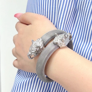 Detalle de pulsera de malla plateada con cabezas de leopardo dobles talladas a mano