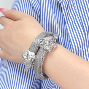 Detalle del brazalete abierto de malla plateada con tallas de cabezas de dragón