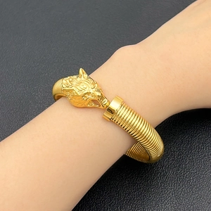 Detalle de brazalete de cabeza de lobo dorado con banda flexible de acero en espiral