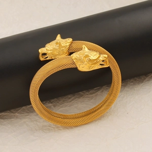 Detalle de pulsera de malla dorada trenzada con terminales tallados de cabezas de lobo