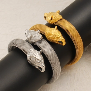 Detalle de pulseras de malla con cabeza de lobo en oro y plata con texturas metálicas