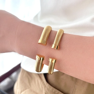 Gros plan du bracelet jonc spirale doré montrant la texture flexible torsadée et les embouts polis
