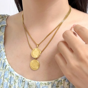 Detail of layered gold Scorpio and Pisces zodiac pendant necklaces worn on neck