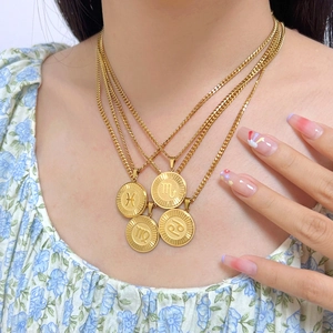 Close-up of layered gold zodiac pendant necklaces on neck with floral dress