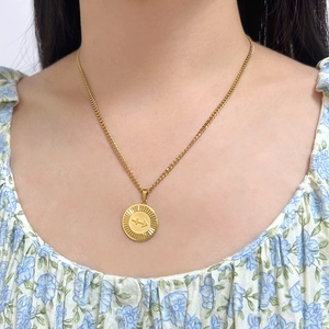 Close-up of gold Sagittarius pendant necklace worn with a floral collar detail