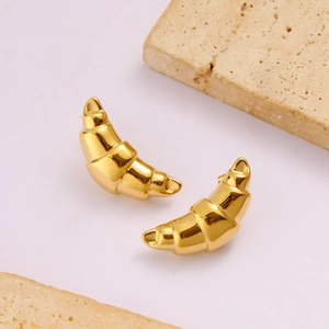 Boucles d'oreilles croissant en or 18K poli sur un fond décoratif en pierre beige