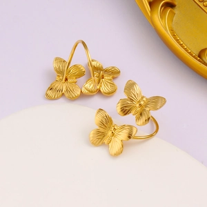Detail of gold double butterfly earrings with fine texture on white stone pedestal