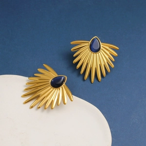 Macro detail of vintage gold fan-shaped earrings with blue teardrop gemstone inlay